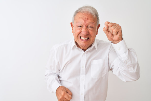 年长的灰白头发的男子穿着优雅的衬衫站在孤立的白色背景愤怒和疯狂举起拳头沮丧和愤怒，同时大喊着愤怒。愤怒和侵略性的概念。图片下载