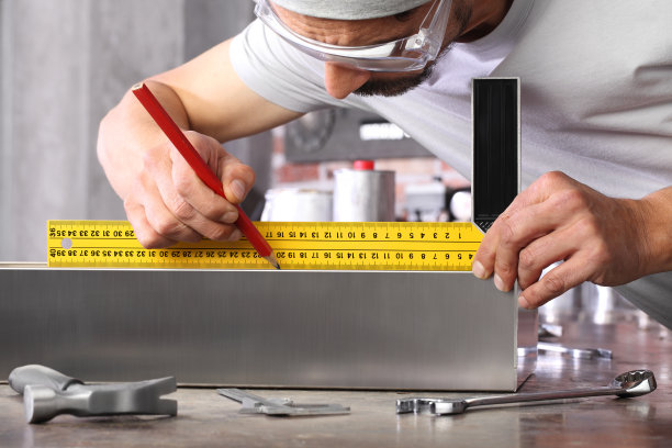 工人在家居车间车库用直尺测量金属角尺和用铅笔，在工作台上用扳手和锤子，diy和工艺概念图片下载