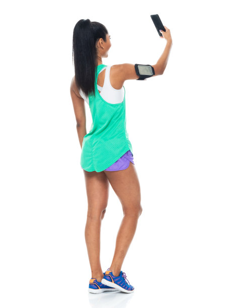 拉丁美洲和西班牙裔的年轻女性穿着背心，用智能手机站在白色背景前拍照图片下载