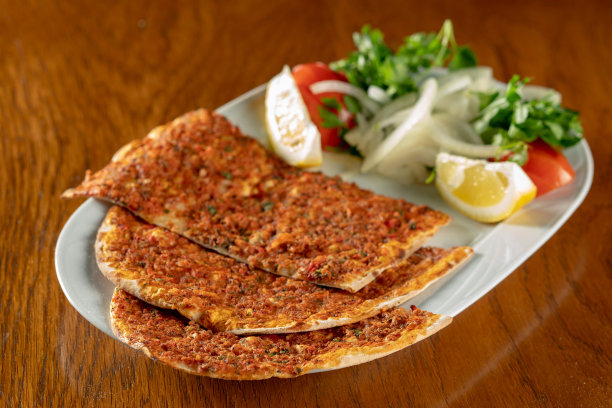 传统的土耳其美食:拉玛昆土耳其美味的披萨与碎牛肉或羊肉，红辣椒，番茄，孜然香料，在乡村木制桌子的背景。库存图片图片下载