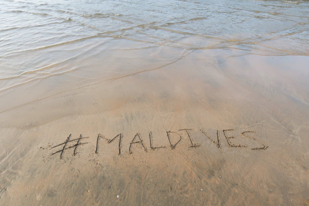 图片的标签标签写在阳光明媚的海滩上，马尔代夫字写在海边的沙子，帕洛伦海滩，印度果阿，概念社交媒体照片的手写在金色的沙子与现代标签前缀图片下载