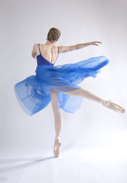 穿着蓝色裙子的年轻女子在工作室跳舞。图片下载