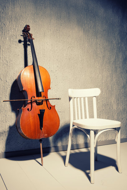 旧的破旧的大提琴和椅子，旁边的灰色纹理墙壁在学校或练习室图片下载