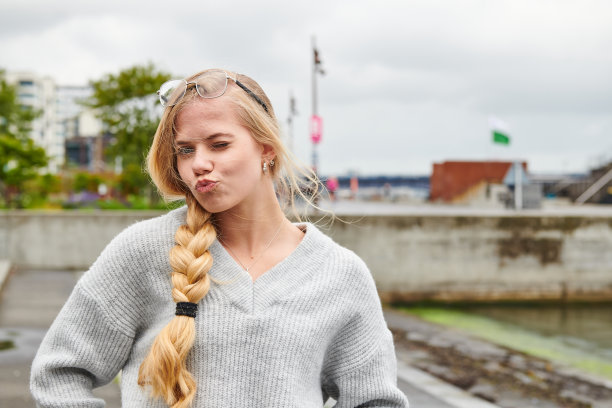 厚脸皮的女人，长头发编着辫子，在镜头前做鬼脸拉嘴唇图片下载