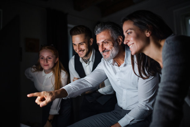 一群商务人士在办公室里用电脑工作到很晚。图片下载