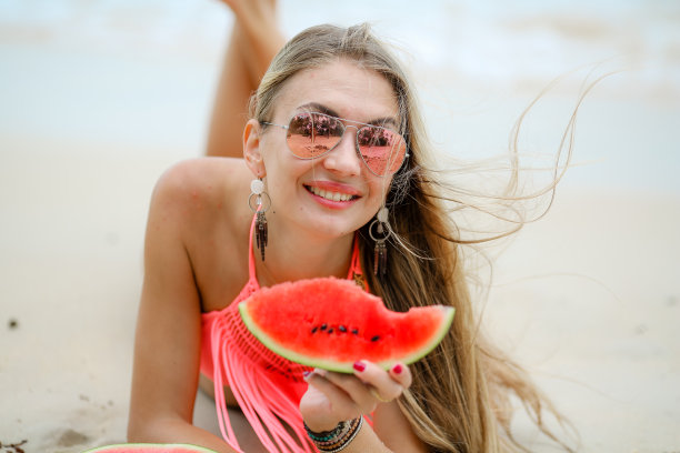 在泰国的海洋上，一个女孩吃着一个成熟多汁的西瓜图片下载