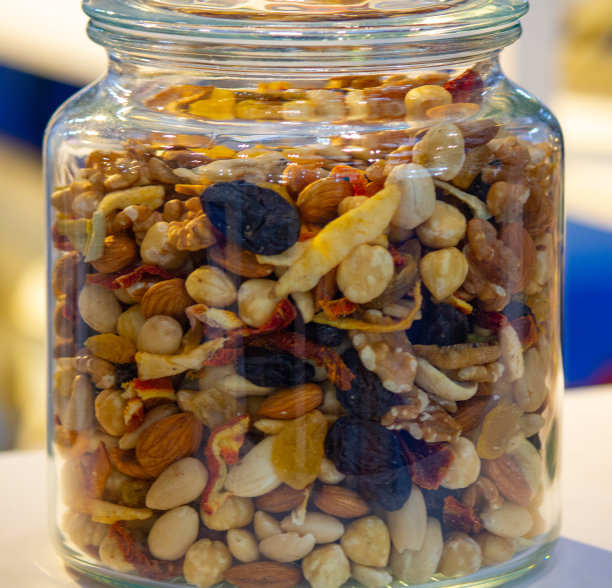 白色木桌上玻璃罐中的各种坚果和种子。素食和有机食品的概念。图片下载
