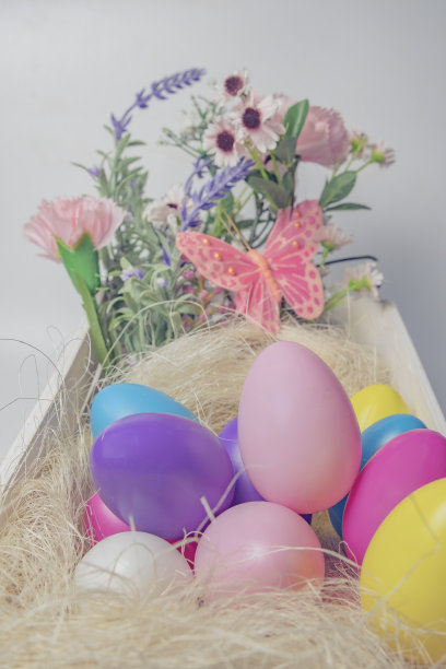 彩色的复活节彩蛋和花在木制的白色盒子与粉红色的蝴蝶在白色的背景。图片下载