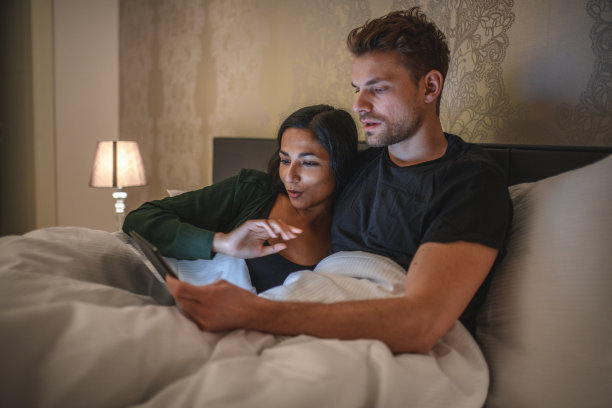 年轻夫妇在家床上使用电子平板电脑图片下载