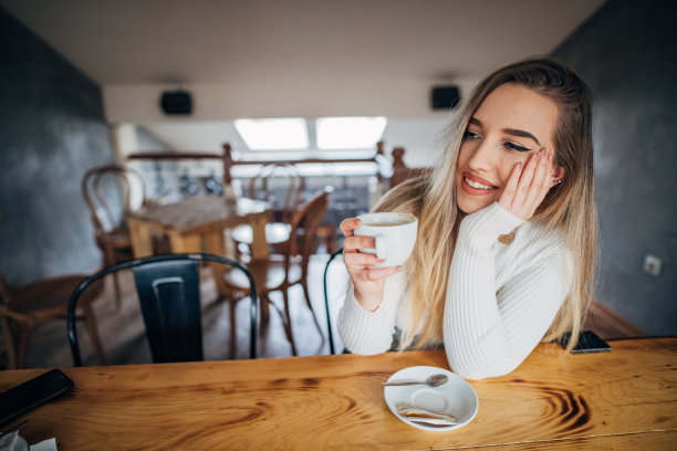年轻女子在咖啡厅喝咖啡，享受时光素材图片