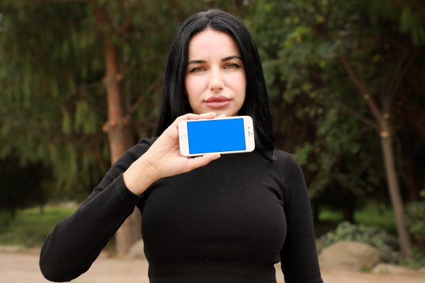 户外肖像美丽的年轻女子与手机图片下载