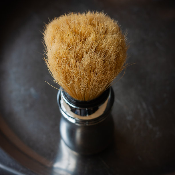 剃须刷在乡村的黑色背景上，在手写体风格的俯视图。男士皮肤护理。放置文本，方形格式。图片下载