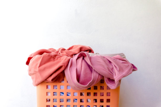 已经穿好的衣服放在篮子里等着洗，主场景是白色的。素材图片