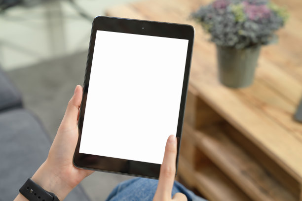 在客厅沙发上手持黑色平板电脑的特写图片下载