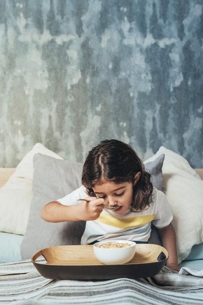 竖版照片：孩子在床上吃早餐图片下载
