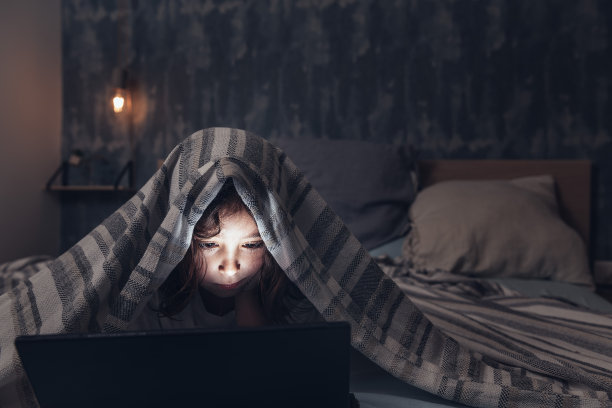 小女孩盖着被子看写字板图片下载