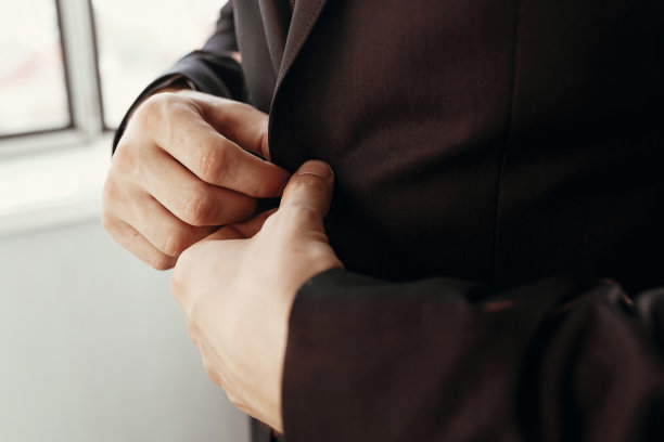 时尚新郎早晨准备，穿棕色西装、白衬衫和红色领带特写。酒店房间内婚礼的早晨准备图片下载