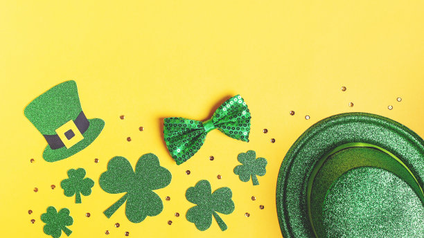 圣帕特里克节的节日卡片上有绿色的三叶草标志，帽子，金色的纸屑。传统的圣帕特里克节绿色服装和黄色背景的装饰。网页横幅，拷贝空间图片下载