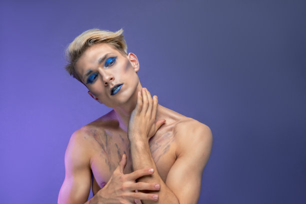 时尚美女肖像的一个男人与金发和干净的皮肤在紫色的背景。专业化妆，唇和眼睛用蓝色眼影和口红，脸的概念，头发护理，复制空间图片下载