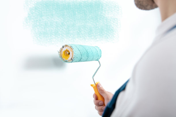 年轻男子用滚筒粉刷墙壁图片下载