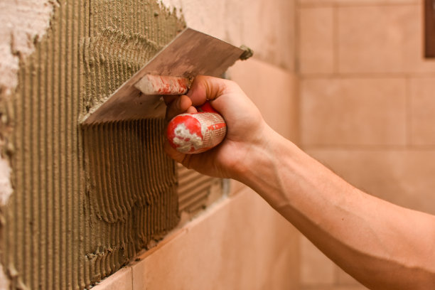 瓦工正在墙上铺设瓷砖图片下载