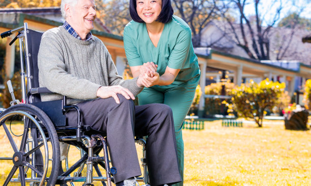 亚洲护士与坐在轮椅上的白人老年患者在一起，户外场景图片下载