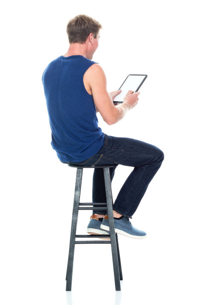 白人男性无袖坐在白色背景前穿着背心和使用数码平板电脑图片下载