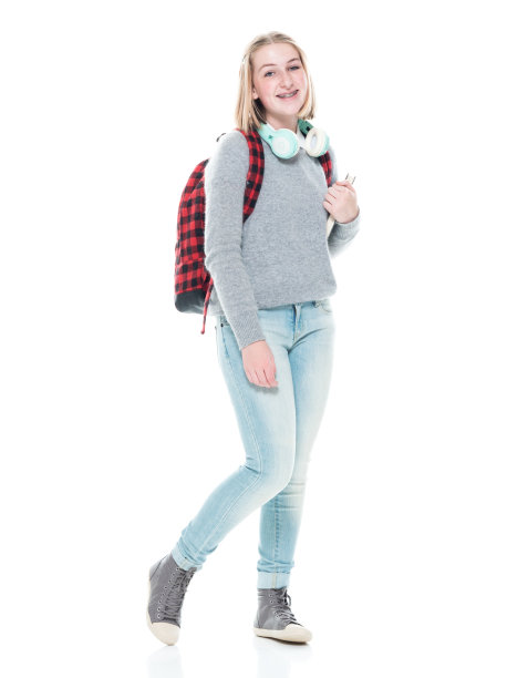 z一代女学生背着背包，拿着课本，戴着耳机站在白色背景前图片下载