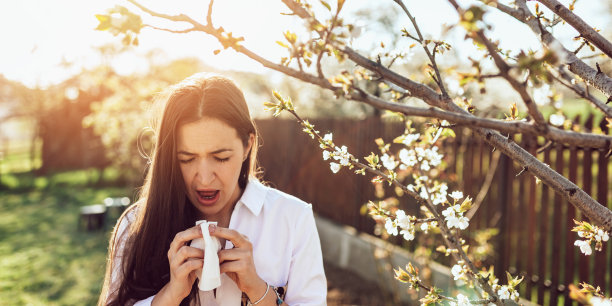 在鲜花盛开的花园里打喷嚏的女人图片下载