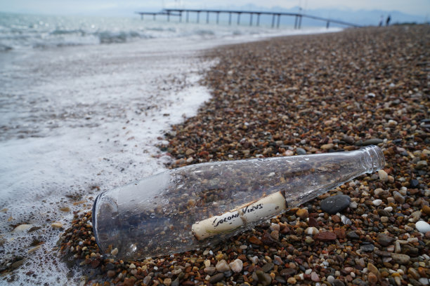 在沙滩上的海浪上有冠状病毒标签的玻璃瓶图片下载