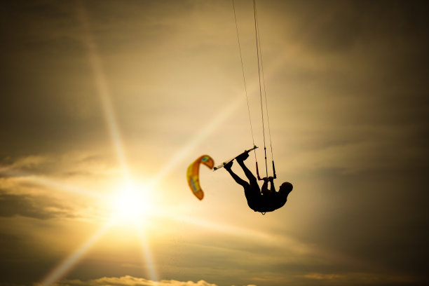 风筝冲浪者在美丽的日落下在空中表演特技图片下载