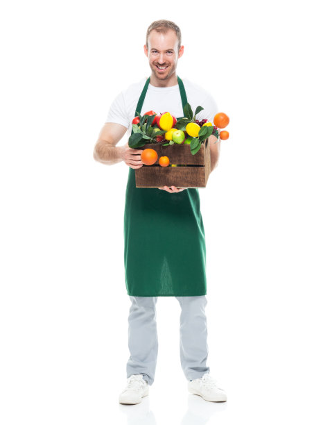 站在白色背景前的年轻白人男农民，穿着围裙，拿着盒子图片下载