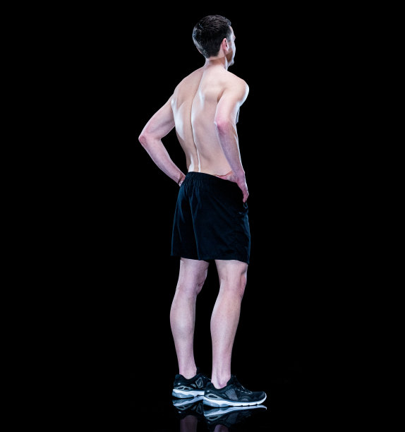 在黑色背景前运动的年轻白人男子，穿着运动鞋图片下载