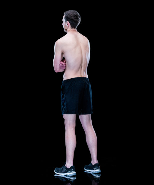 在黑色背景前运动的年轻白人男子，穿着运动鞋图片下载