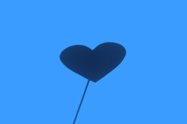 一个模糊的心的影子在一根棍子上纹理白色的背景。略带经典的蓝色趋势2020年图片下载