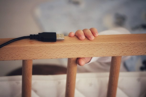 USB数据线和婴儿床上的婴儿手图片下载