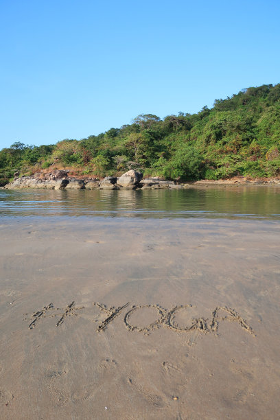 图片的标签标签写在阳光明媚的海滩上，瑜伽词写在海边的沙子，帕洛伦海滩，印度果阿，概念社交媒体照片的手写在金色的沙子与现代标签前缀图片下载