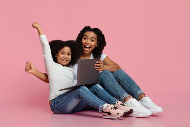 快乐的非洲裔妈妈和小女儿坐在笔记本电脑旁，庆祝成功图片下载