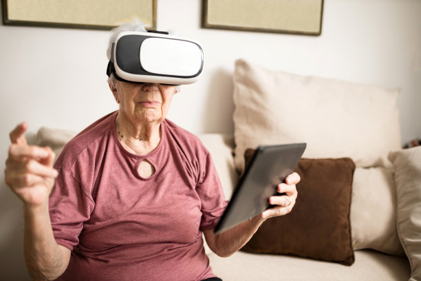 资深女性坐在客厅的沙发上，戴着虚拟现实眼镜图片下载