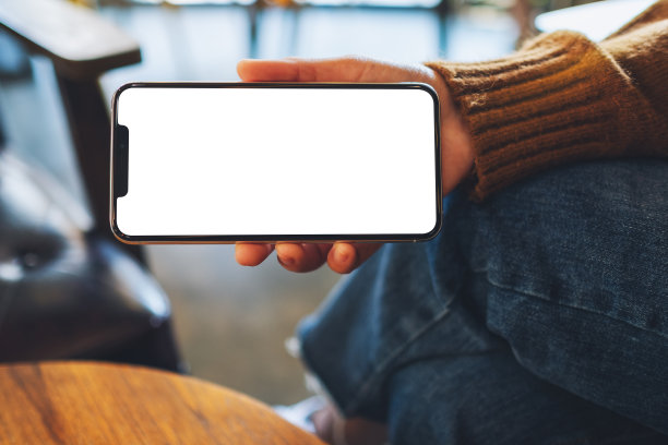 在咖啡馆里，女人手持并展示黑色空白屏幕的手机图片下载