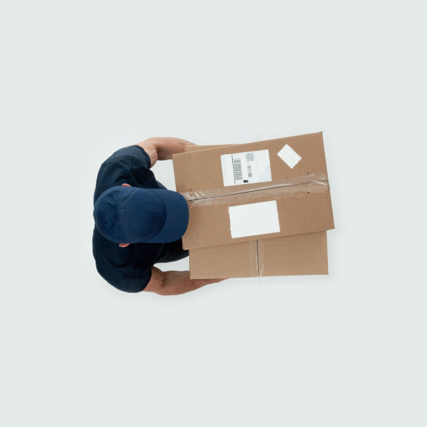 白人年轻男性送货员，穿着衬衫，拿着集装箱走在白色背景前的送货车旁图片下载