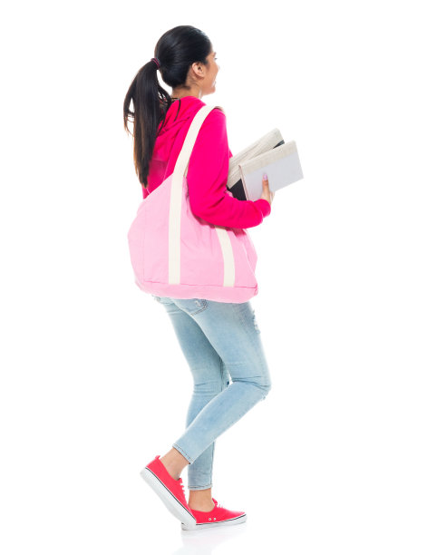 z一代女学生穿着牛仔裤拿着课本走在白色背景前图片下载