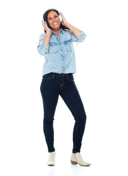中年白人女性穿着裤子戴着耳机站在白色背景前图片下载