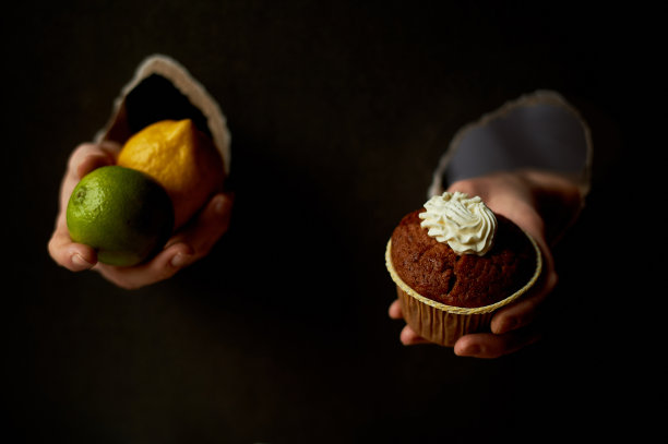 拼贴画。把纸的孔交进去。拿着一个纸杯蛋糕和一个柠檬。对着甜美的果实。饮食或暴食。趋势，文本的位置图片下载