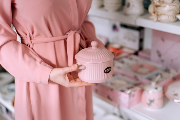 一个女孩的手拿着一个粉红色的平底锅在一家餐具店。图片下载