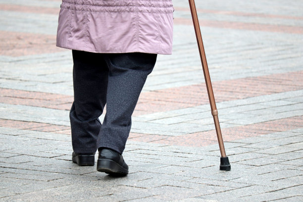 拄着拐杖沿街行走的一瘸一拐的妇女图片下载