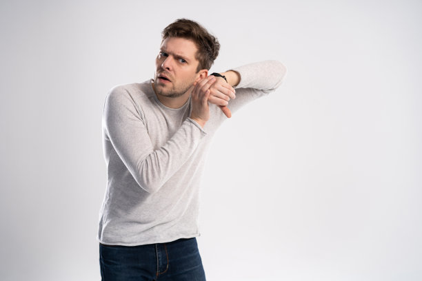 一名震惊的男子在白色背景上看手表的肖像。图片下载