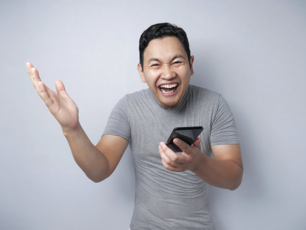 震惊的快乐男人看着智能手机图片下载