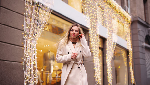 一位戴着无线耳机的迷人女孩走在有散景灯光的街道上图片下载