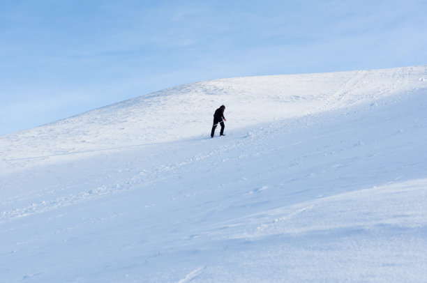 一个孤独的人爬上白雪覆盖的小山图片下载